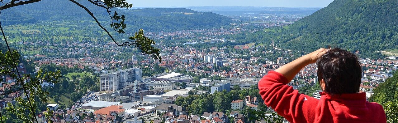 Panoramablick auf die Stadt Geislingen an der Steige von oben, mit einer Person im roten Pullover, die mit dem Rücken zum Betrachter steht und in die Ferne blickt.